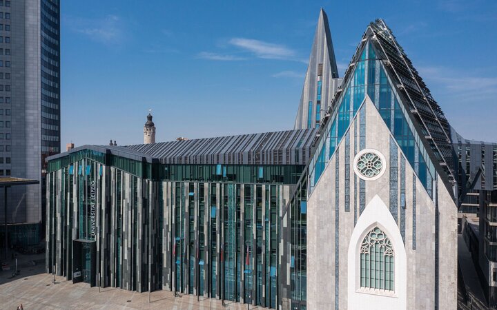 Foto eines futuristisch anmutenden Kirchenbaus mit viel Glas neben einem Hochhaus